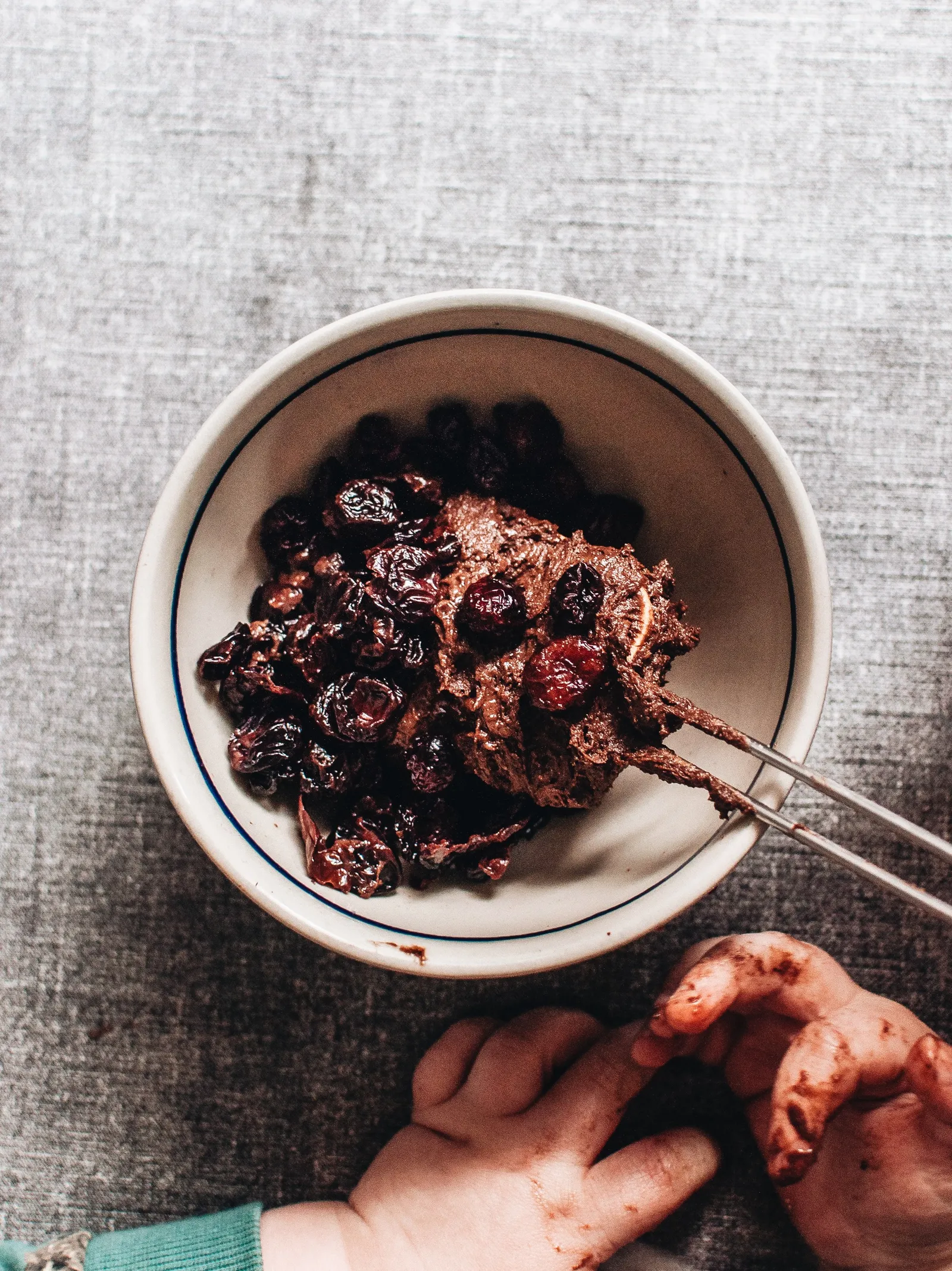 Nahaufnahme eines saftigen, tiefbraunen Brownie-Cookies mit glänzender Oberfläche und kleinen roten Kirschtupfern.