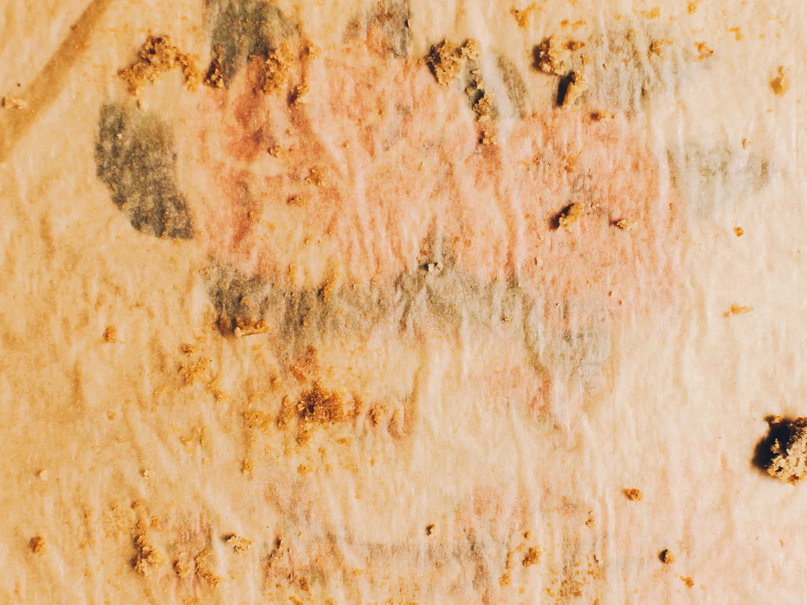 Gebrauchtes Backpapier mit Fettflecken und Krümeln nach dem Backen der Blondies.