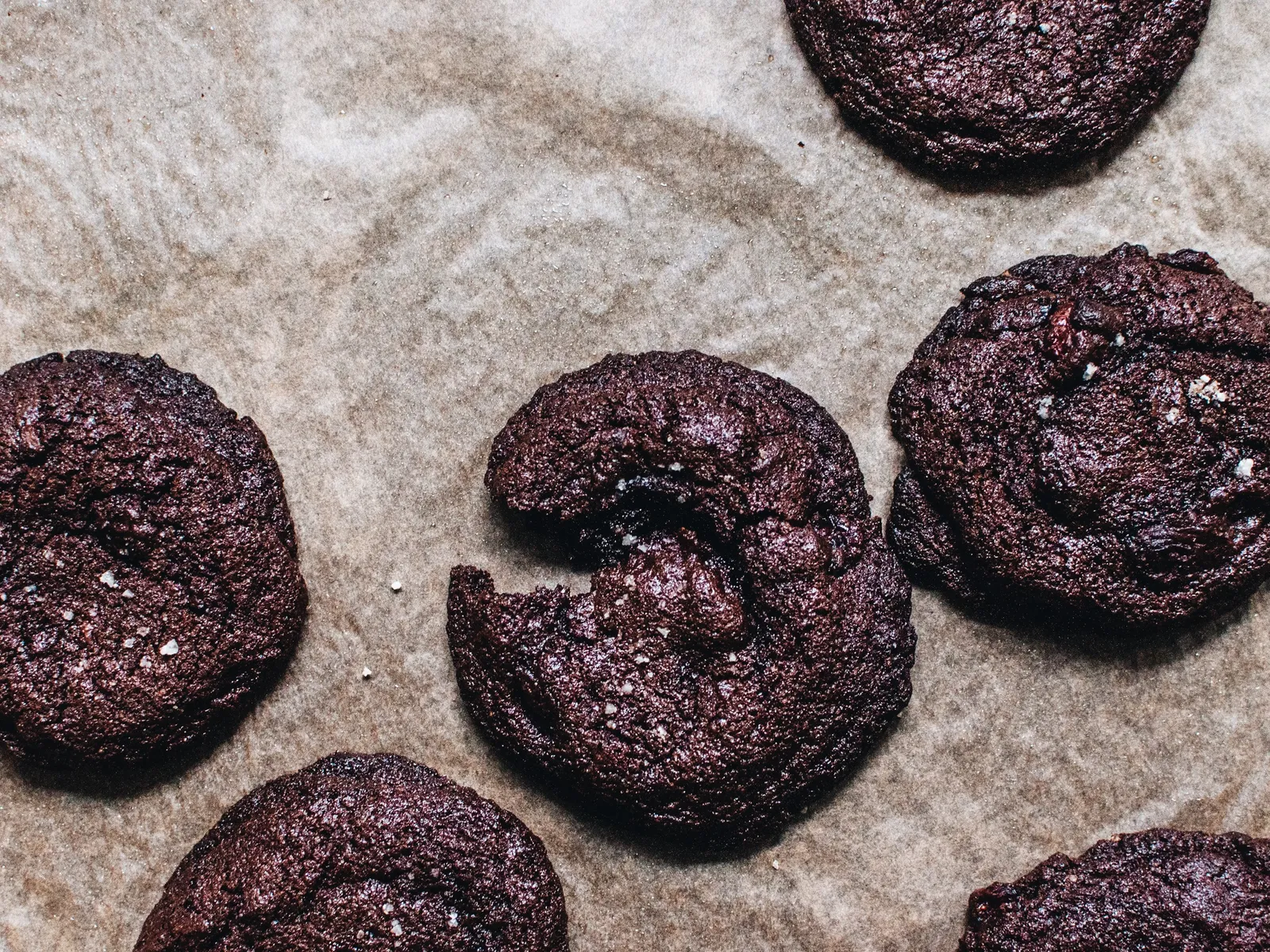 Eine weiße Schüssel mit in Schokolade getränkten Kirschen und einem Stück dunklem Brownie-Teig, daneben kleine Kinderhände mit Schokoladenspuren.